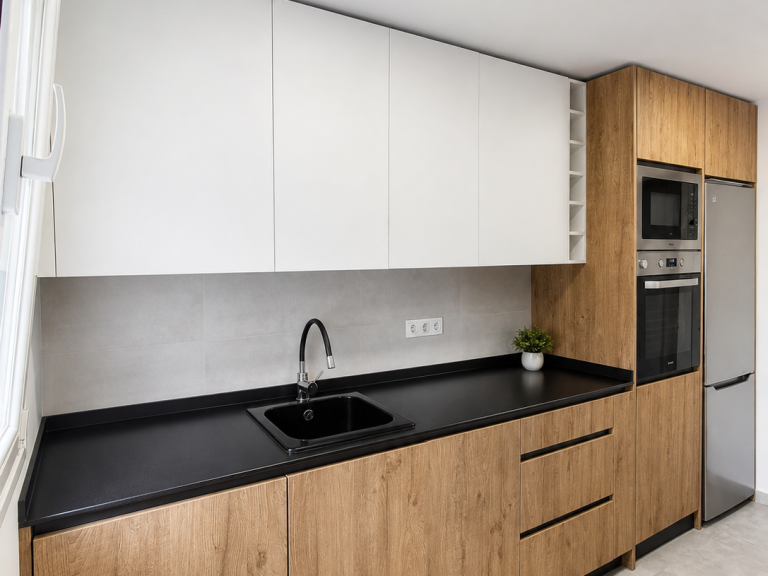 Cocina reformada con mobiliario de madera y encimera negra